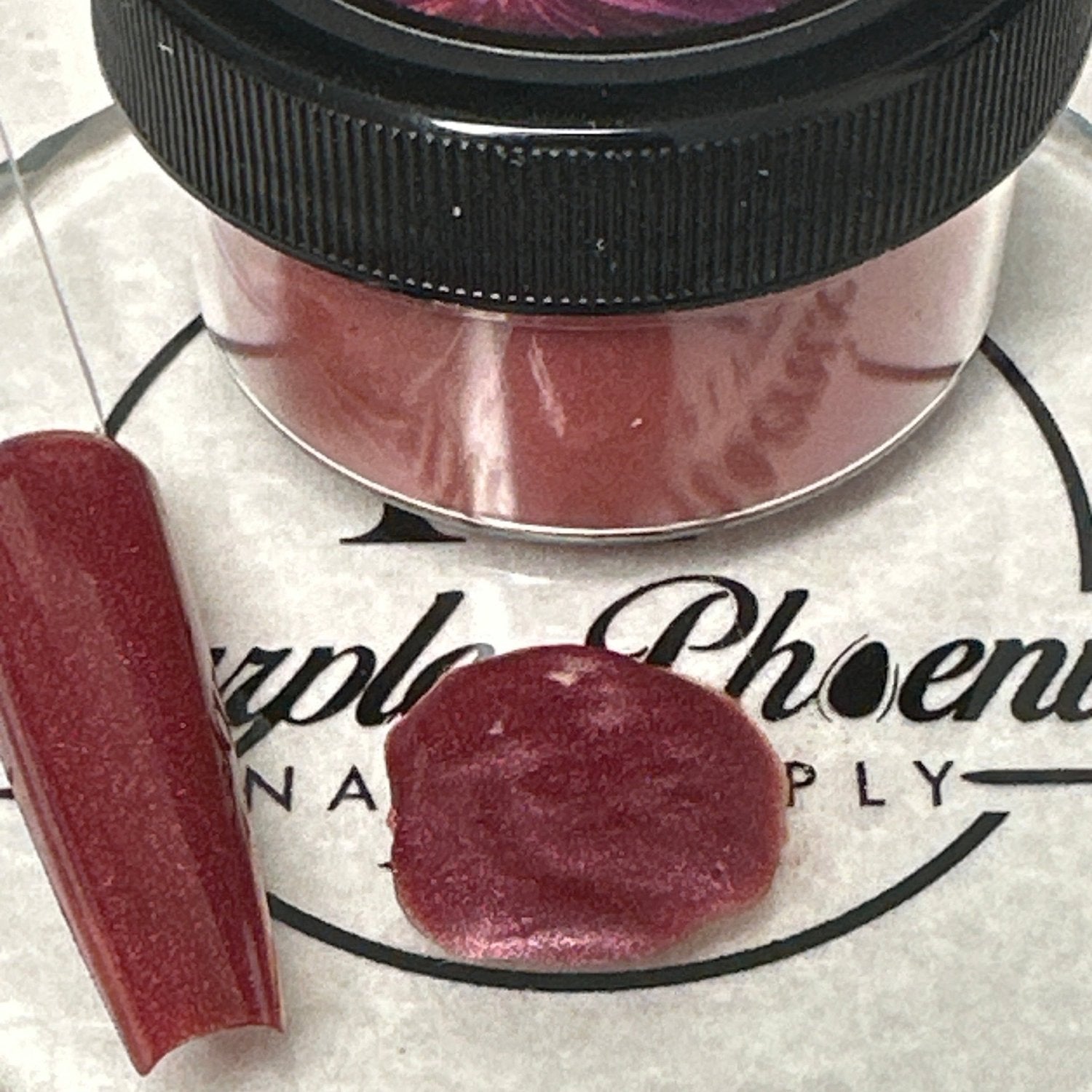 Close-up of Maroon Mirage Acrylic Powder - dark maroon with a shimmering effect, applied on a nail tip, highlighting its sophisticated and luxurious appearance.