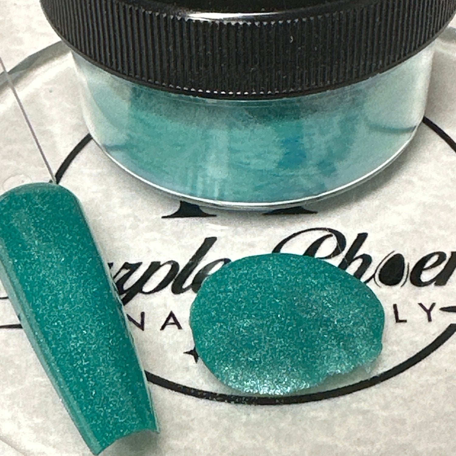 Close-up of Tahitian Splash Acrylic Powder - a vivid turquoise with a subtle, sparkling effect, applied on a nail tip, highlighting its lively, island-inspired appearance