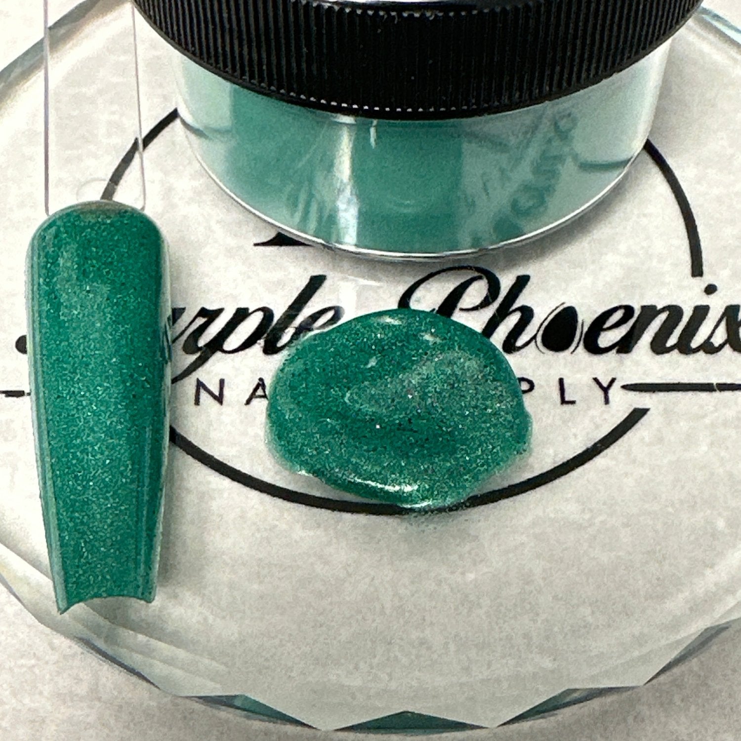 Swatch of Emerald Lagoon Acrylic Powder - a shimmery teal shade with a hint of greenish-blue, applied on a nail tip, showcasing its vibrant, lagoon-inspired finish.