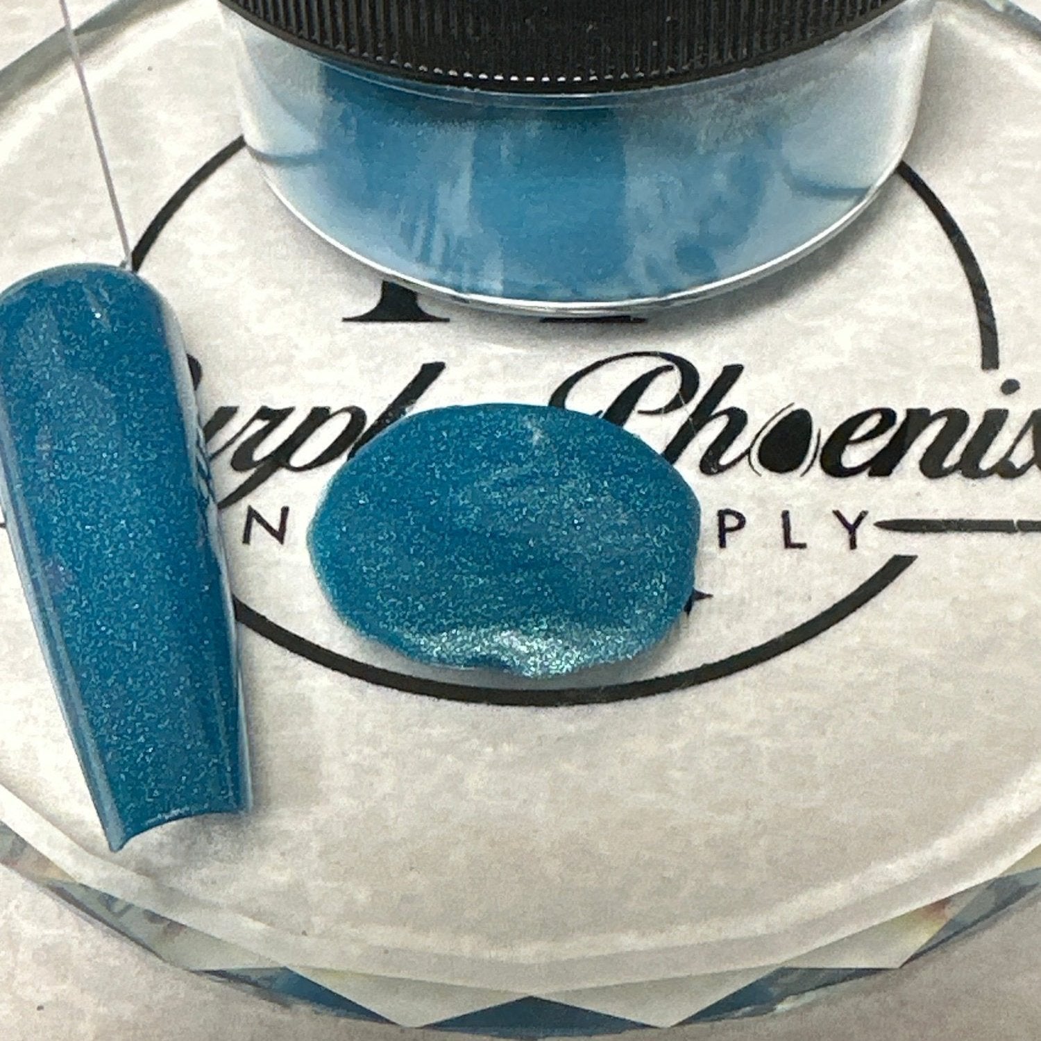 Close-up of Tidal Teal Acrylic Powder - a deep teal with a soft, shimmering effect, applied on a nail tip, highlighting its smooth and bold appearance